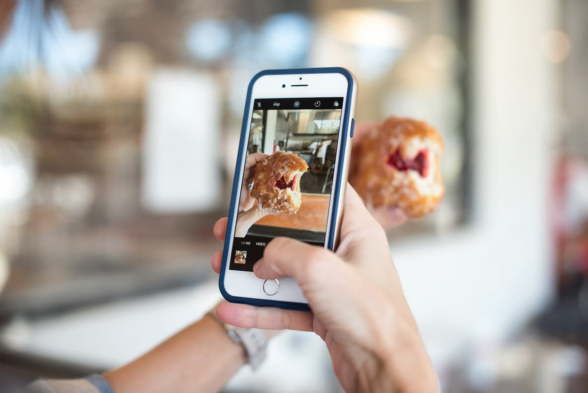 Person taking a picture of a pastry they are holding