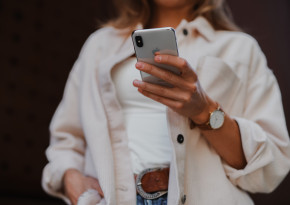 girl with white shirt, jeans and an iphone in her hands.